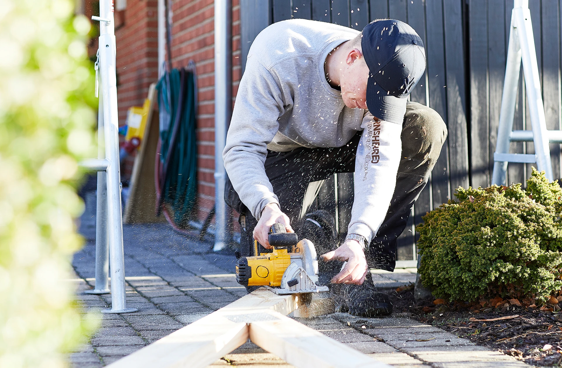 Mand arbejder med en rundsav på et byggeprojekt i Lejre Kommune