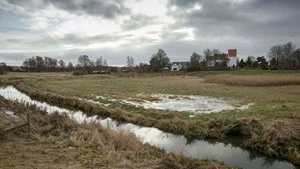 Vandløb i naturlandskab med skyer i baggrunden