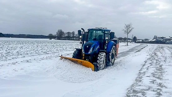 Traktor med plov på snefyldt vej